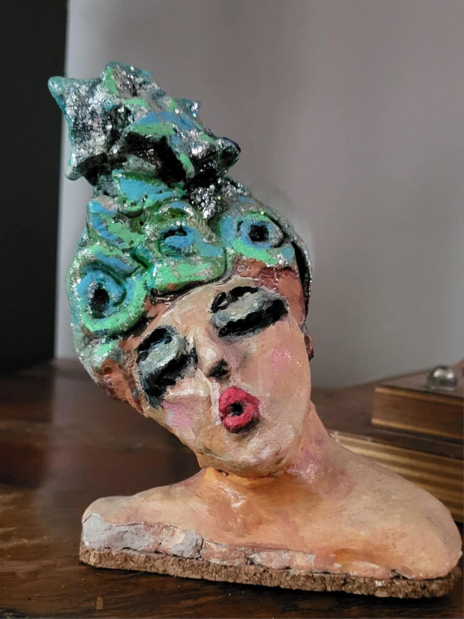 original clay piece by singerluciewalker - a bust of a whimsical female with pursed lips and large closed eyes, wearing a fancy sparkly headress, with her head tilted